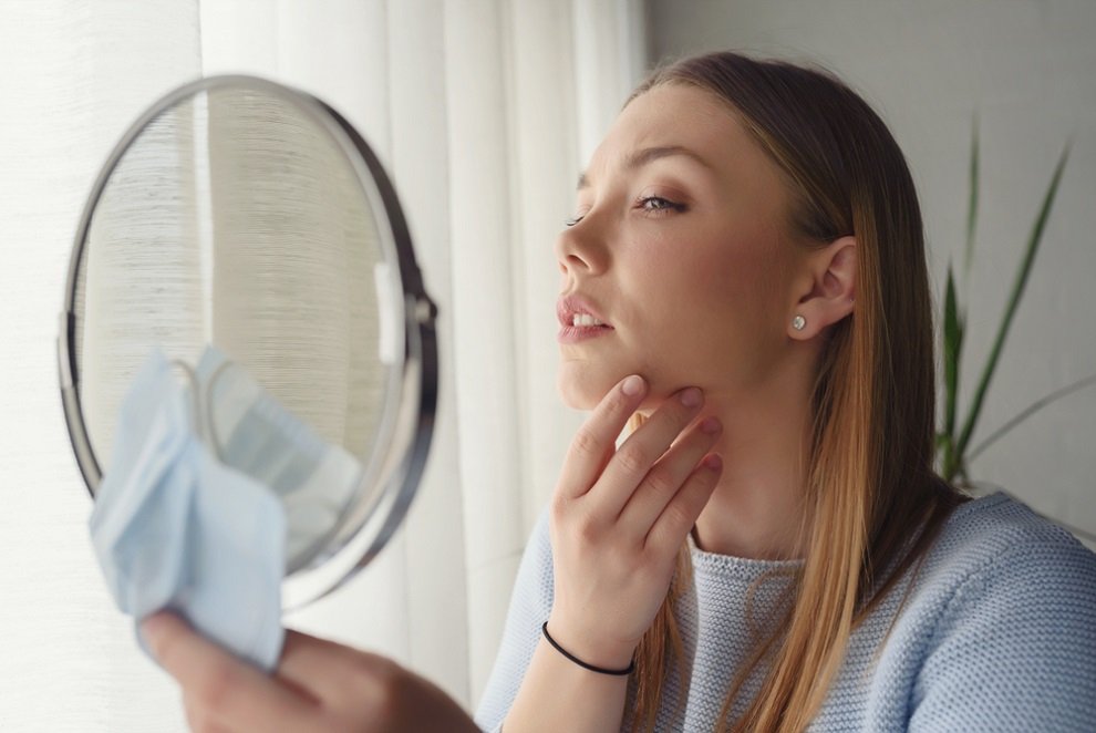 woman looking at mirror to check her skin