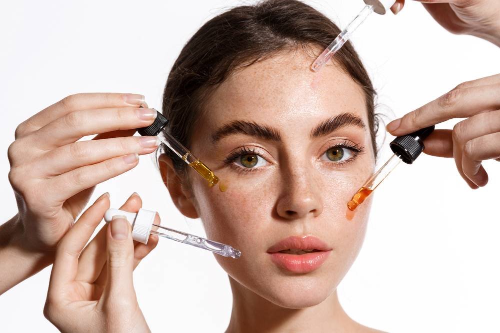 Woman applying various skincare products to her face